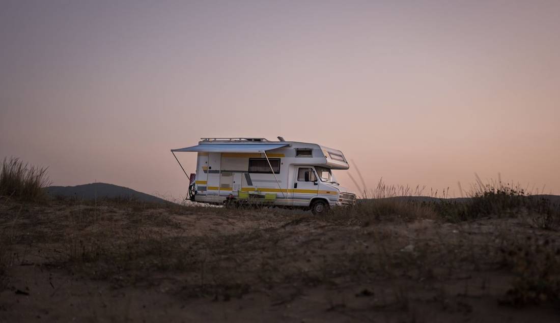 An RV parked in nature at sunset