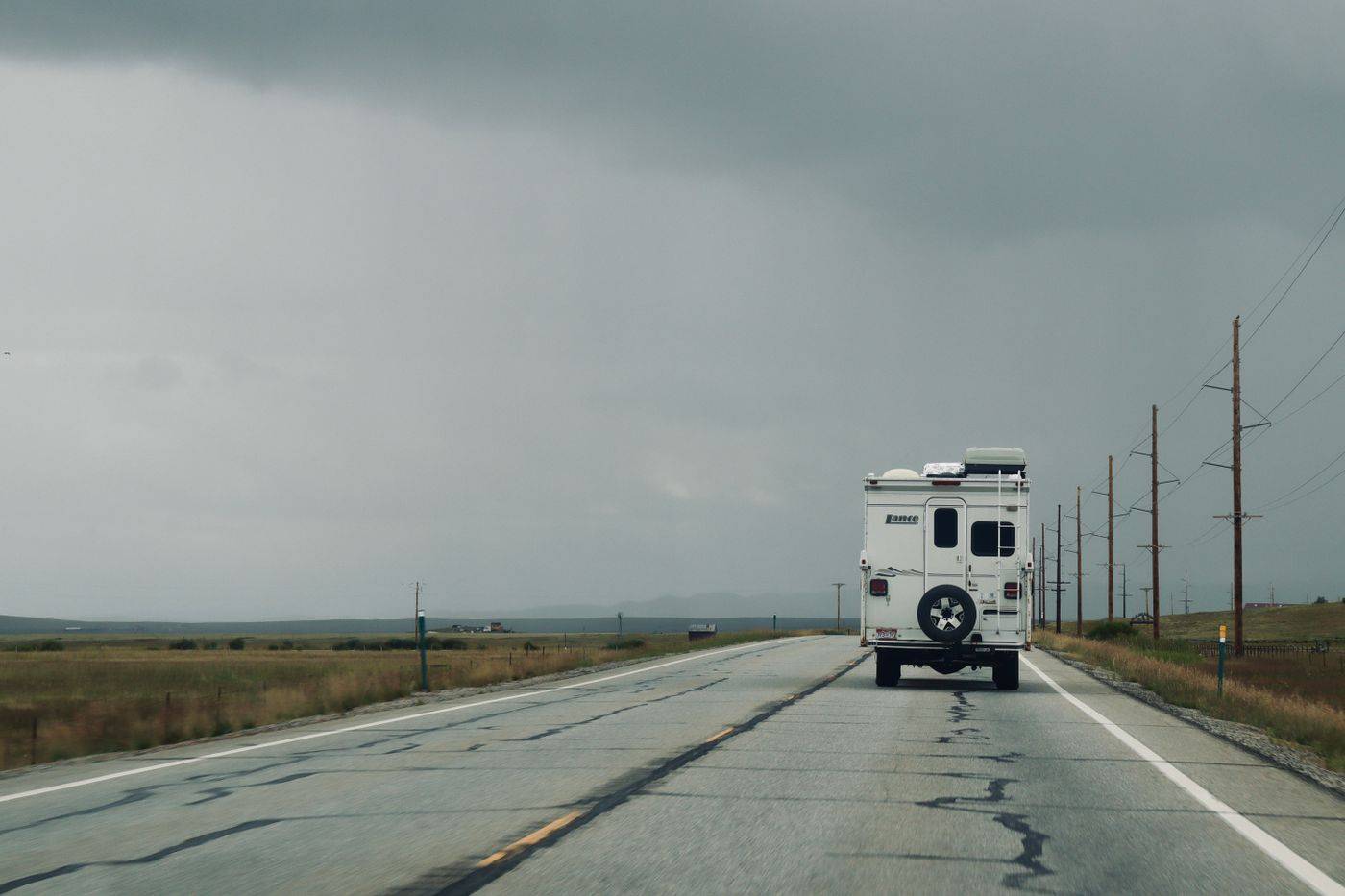 A lone RV on an empty highway under dark clouds
